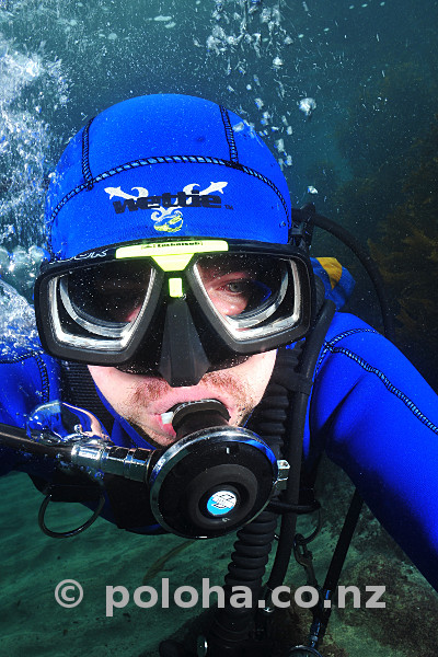 Front image of scuba diver breathing from vintage two-stage regulator